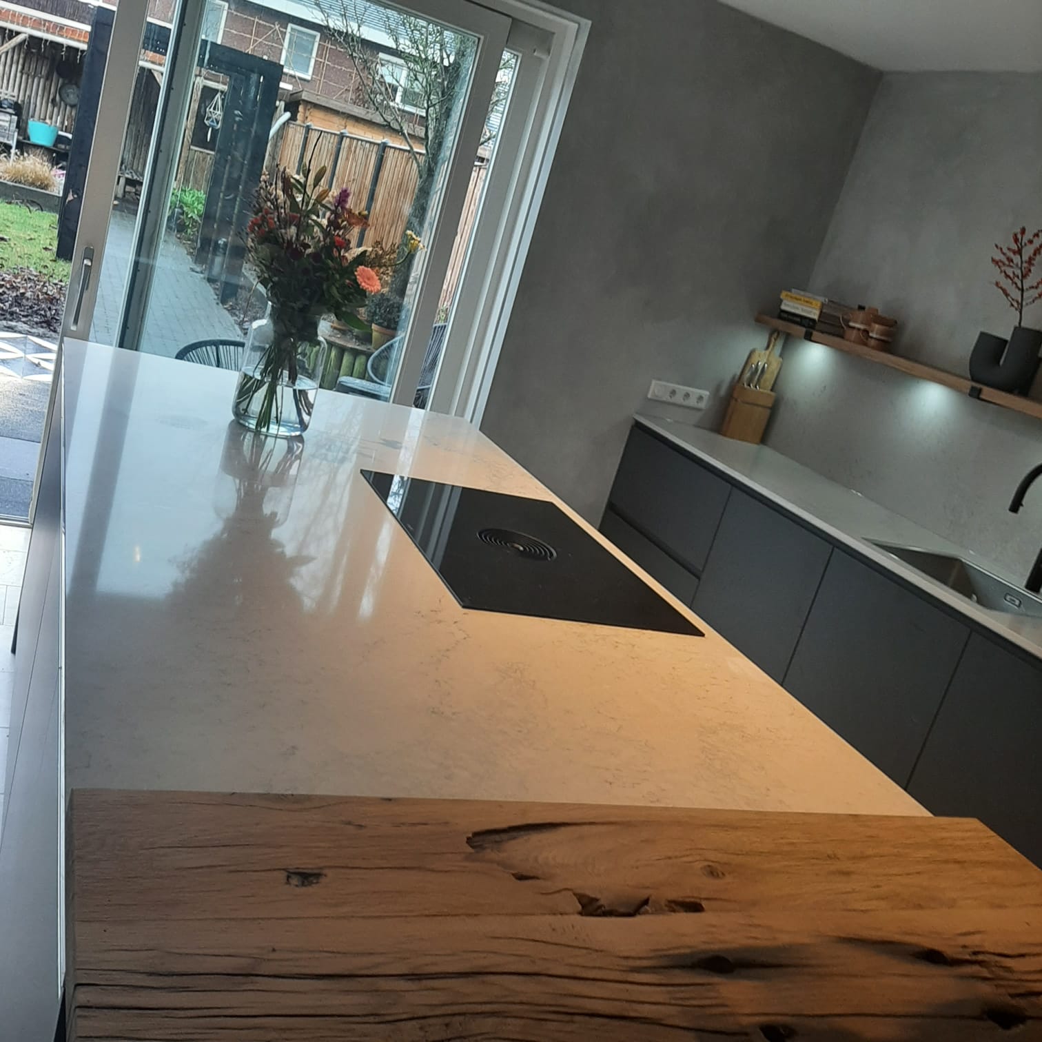 Kookeiland met wit stenen blad en een bar van oud eikenhout