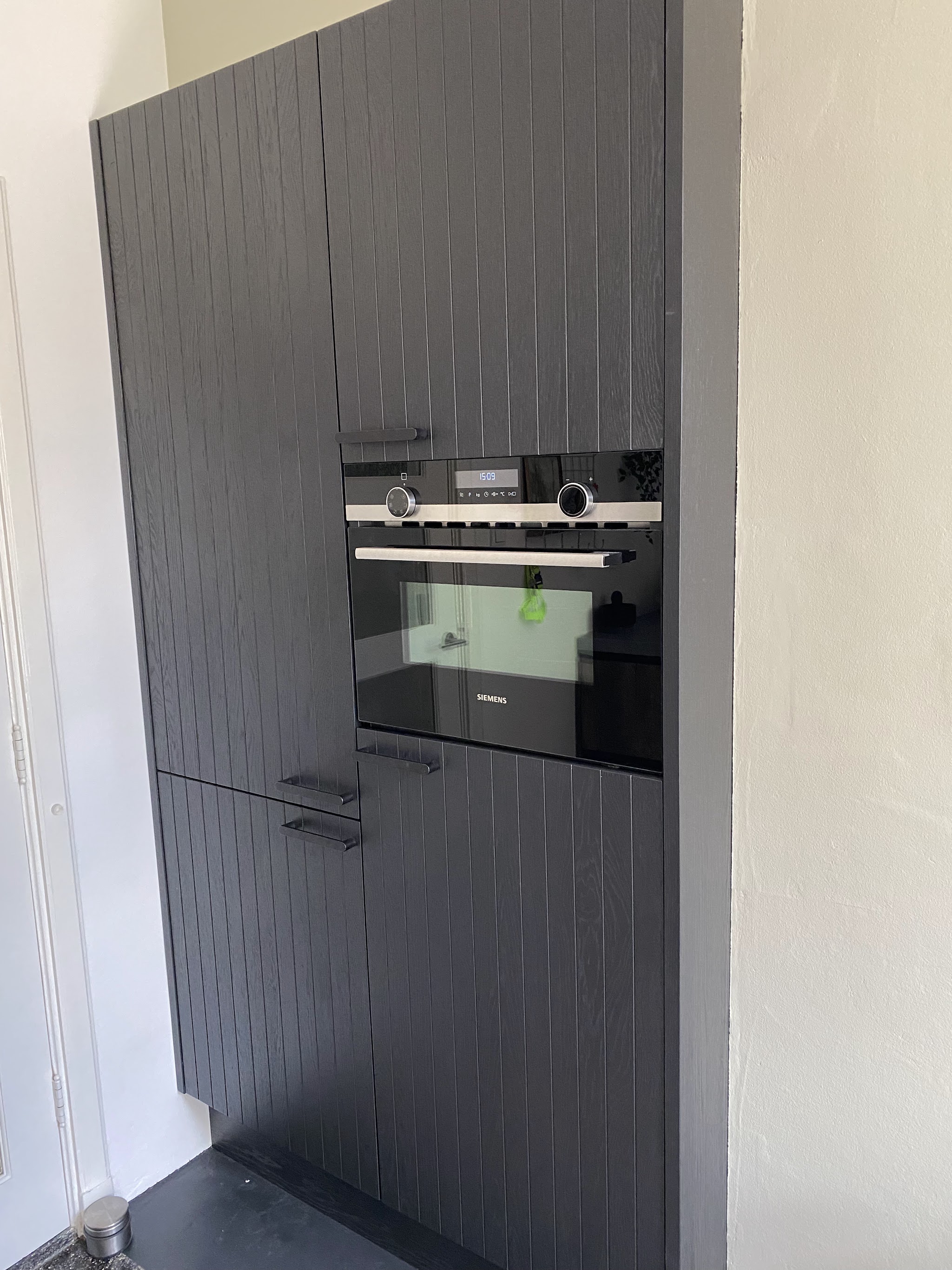 Hoge kastenwand met ingebouwde oven en magnetron in donkere fronten